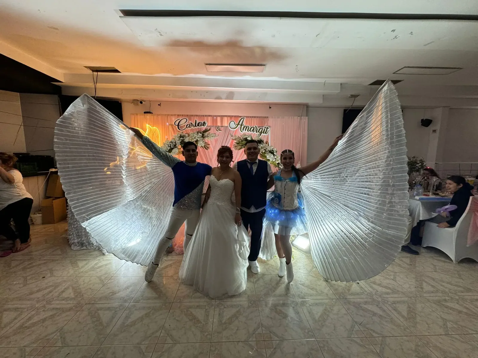 Artistas con alas luminosas animando una celebración de boda