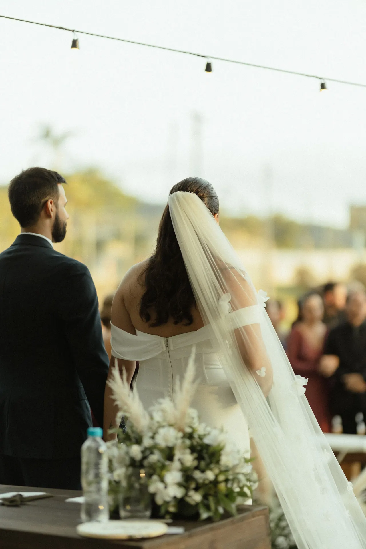 Novios de espaldas frente a sus invitados durante una ceremonia al aire libre